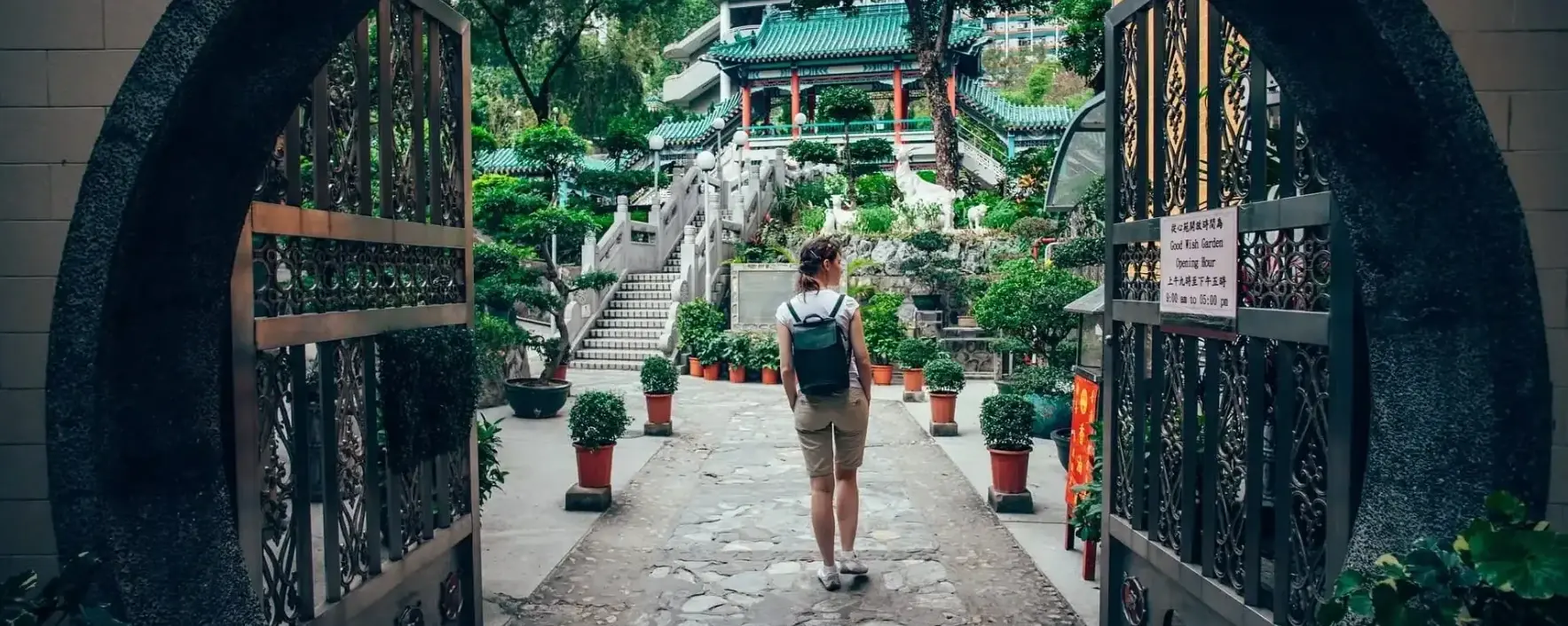 Young person with back pack entering a park with traditional Chinese architecture